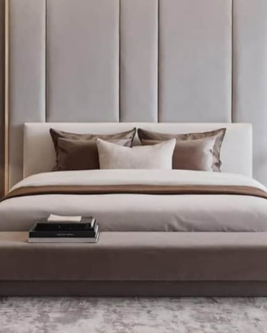 Modern bedroom with upholstered headboard, neutral bedding, brown bench at foot of bed, pendant lights, and taupe curtains