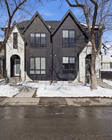 Covered balcony with black metal railing overlooking suburban neighborhood with houses and bare trees